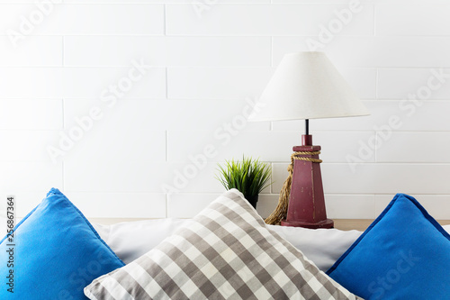 Lamp and green plant on bedside with blue and grey pollows. Hotel room interior background. Text space photo