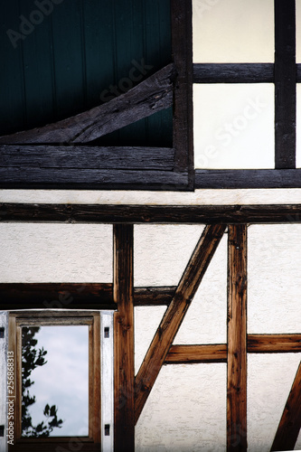 Die Balkenkonstruktion und das Holzger  st eines nostalgischen Fachwerkhauses mit vergilbter Fassade..