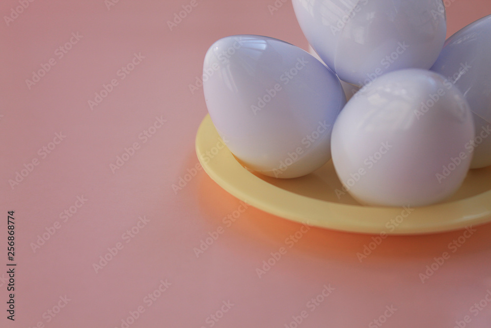 White eggs on the background in pink pastel color. Small plastic toy eggs. Kids toys. Minimalism food concept. Easter concept.Pink and white background.