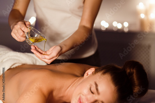 Masseur pouring aroma oil on hand, preparing for massage photo