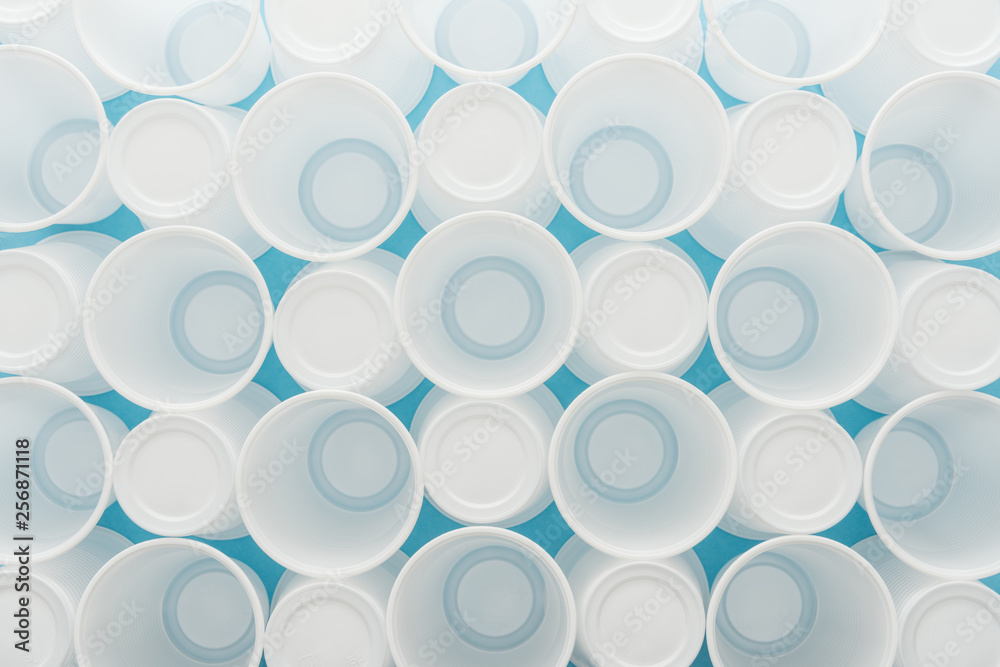 top view of white plastic cups on blue background
