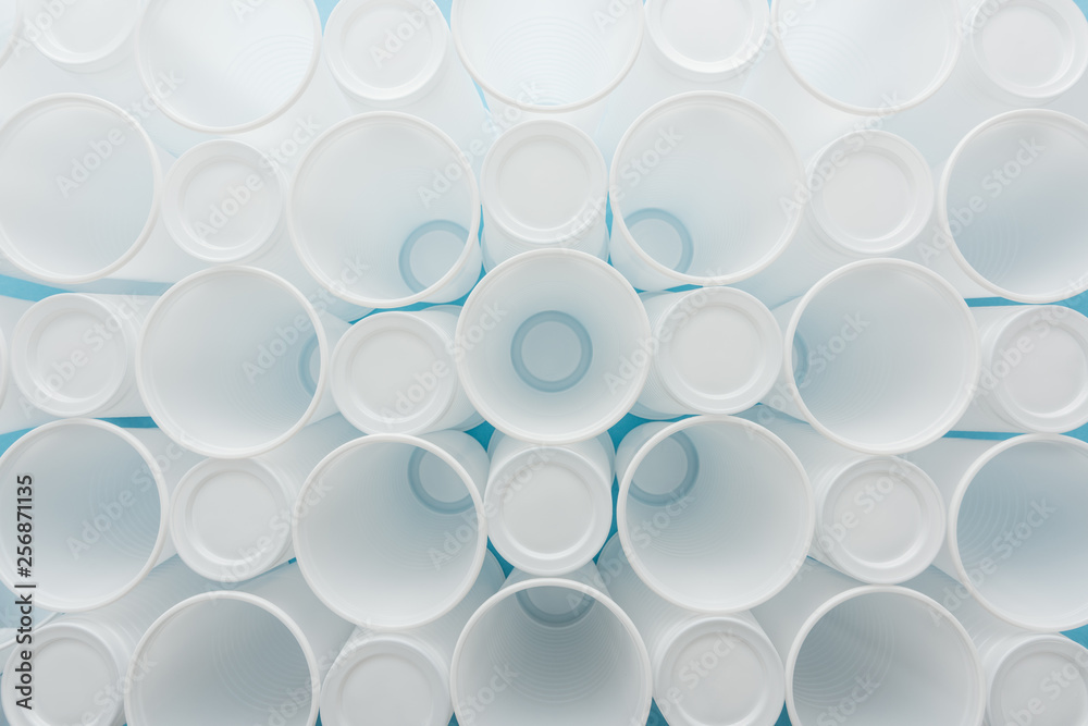 top view of white and plastic cups on blue background