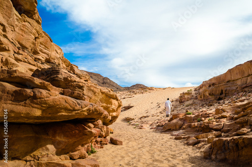 man in white arab clothing walks in a colored canyon in Egypt Dahab South Sinai