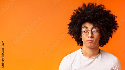Skeptical young man looking aside at free space