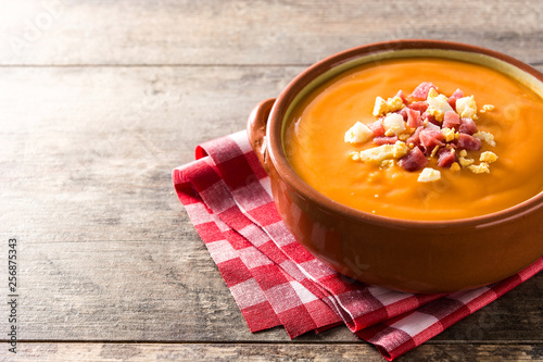 Typical Spanish salmorejo cream with ham and egg on wooden table. Copyspace photo