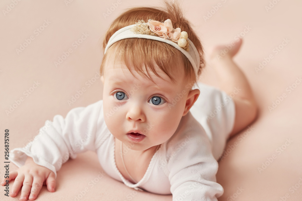 a girl of four months lies on a light pink background a girl of four months lies on a light pink background