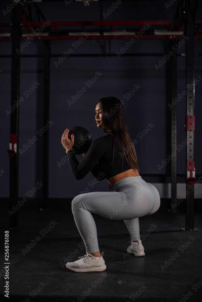Attractive asian woman doing  exercises with a medicine ball. Asian athlete girl doing exercise working out with heavy weighted ball.