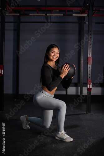 Attractive asian woman doing exercises with a medicine ball. Asian athlete girl doing exercise working out with heavy weighted ball.