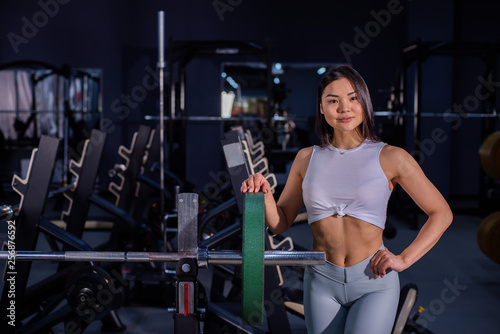 Girl adds weight to the bar. Asian woman adding weight on a bar as she workout in fitness gym