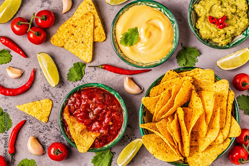 Mexican food background: guacamole, salsa, cheesy sauces with nachos