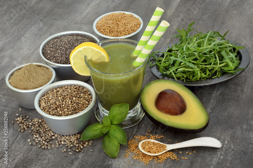 Juice smoothie health drink with avocado, ruccola, basil herb, flax, chia, hemp seed and food supplement powder on rustic wood background. High in omega 3, antioxidants, vitamins and dietary fibre.