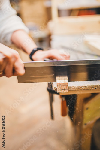 Carpentry workshop - professional and qualified woodworking and crafting- cut with a hacksaw