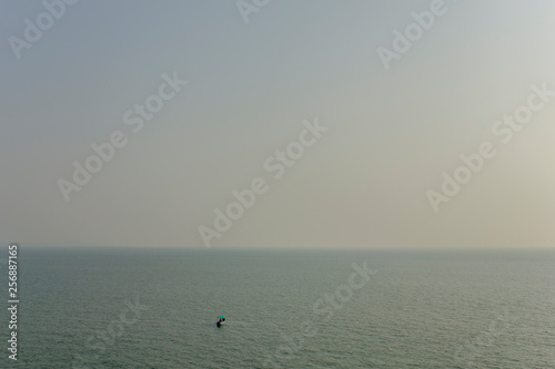 pleasure boat in the open sea on the background of the ocean horizon under a gray sky, aerial view
