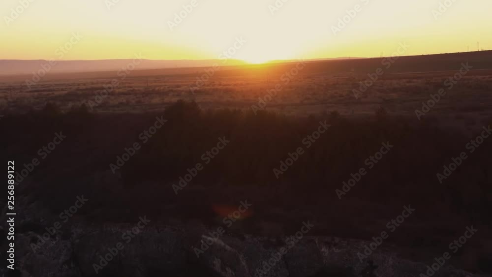 Drone up from height aerial view stony sheer cliffs and bright late sunset on sunny day in spring. Large panorama of beautiful highlands. Orange field and horizon. Lens flare. Relax tourist Drone up from height aerial view stony sheer cliffs and bright late sunset on sunny day in spring. Large panorama of beautiful highlands. Orange field and horizon. Lens flare. Relax tourist