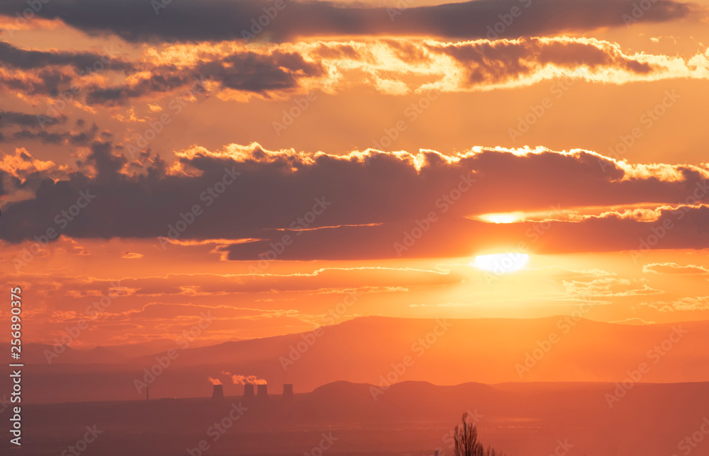 The golden hour of sunset. Orange sky with clouds and yellow sun shining over the mountains. The golden hour of sunset. Orange sky with clouds and yellow sun shining over the mountains.