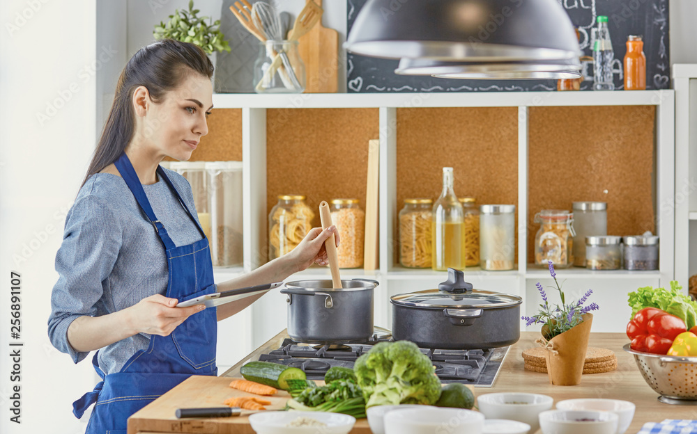 Happy woman looking recipe tablet kitchen reading cooking