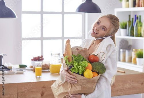 Young woman holding grocery shopping bag with vegetables Standi