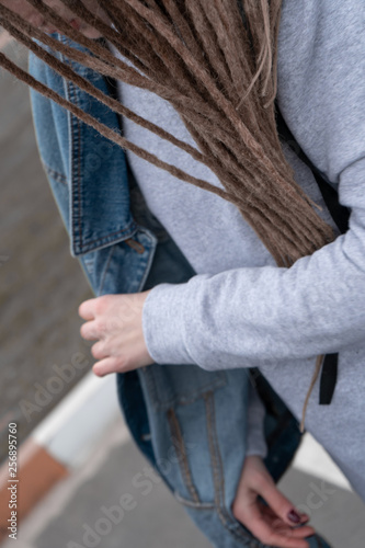 Close-up. Girl with dreadlocks in a sweatshirt and jeans walk the street
