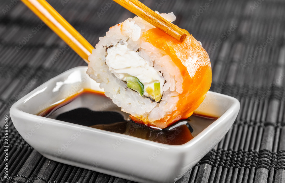 sushi roll dipped in soy sauce Stock Photo | Adobe Stock