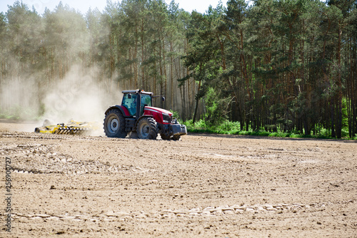 Traktor orzący pole pod zasiew, prace w polu na wiosnę