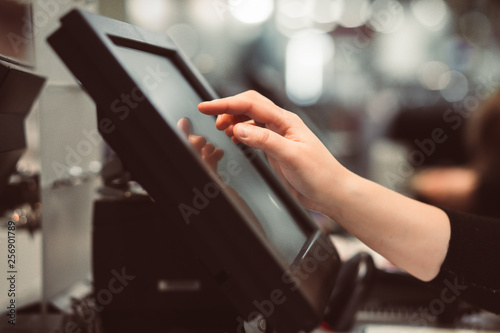 Young woman hand doing process payment on a touchscreen cash register, finance concept (color toned image)