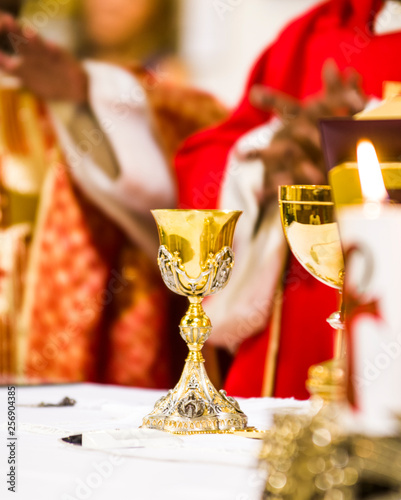 hands of the priest consecrate wine and bread on the altar of holy mass photo