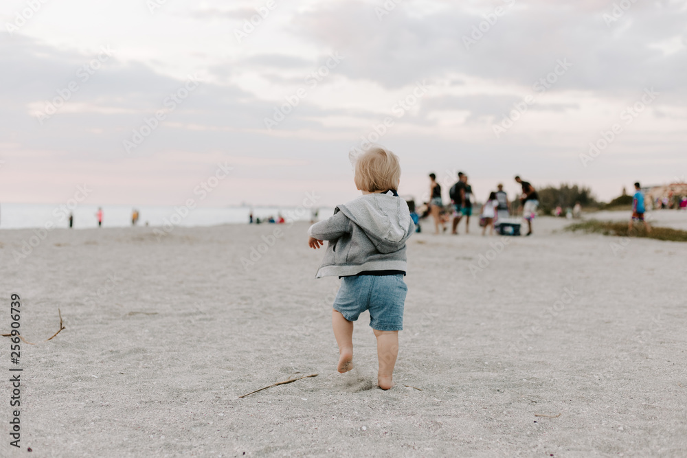 Portrait of Cute Little Baby Boy Child Playing and Exploring in the Sand at the Beach During Sunset Outside on Vacation in Hoodie Zip-Up Sweat Shirt