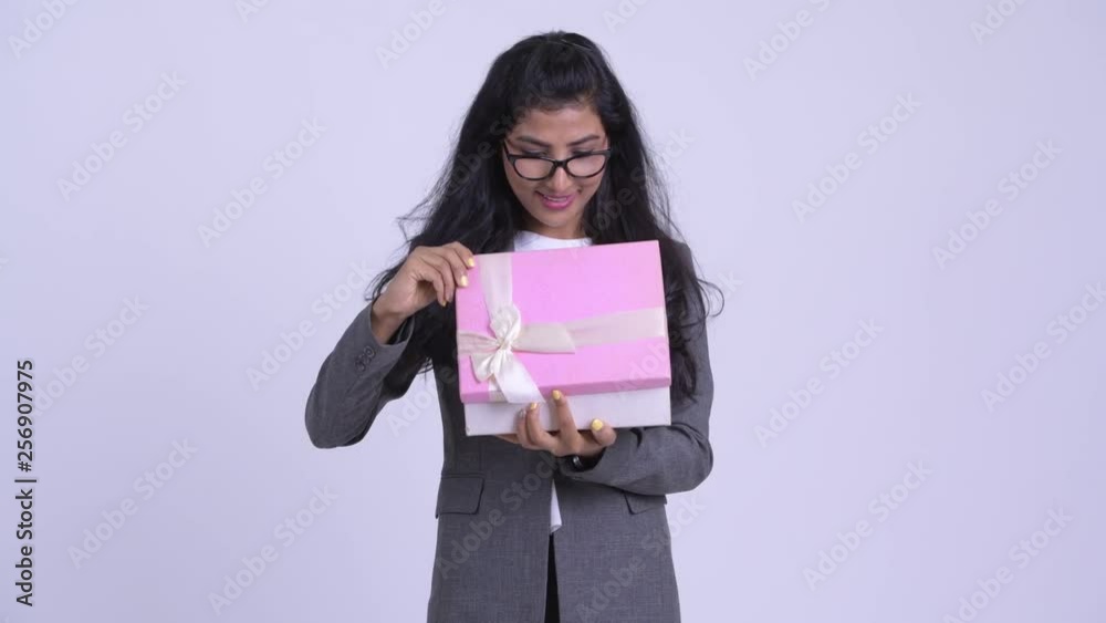 Young happy Persian businesswoman opening gift box and looking surprised Young happy Persian businesswoman opening gift box and looking surprised
