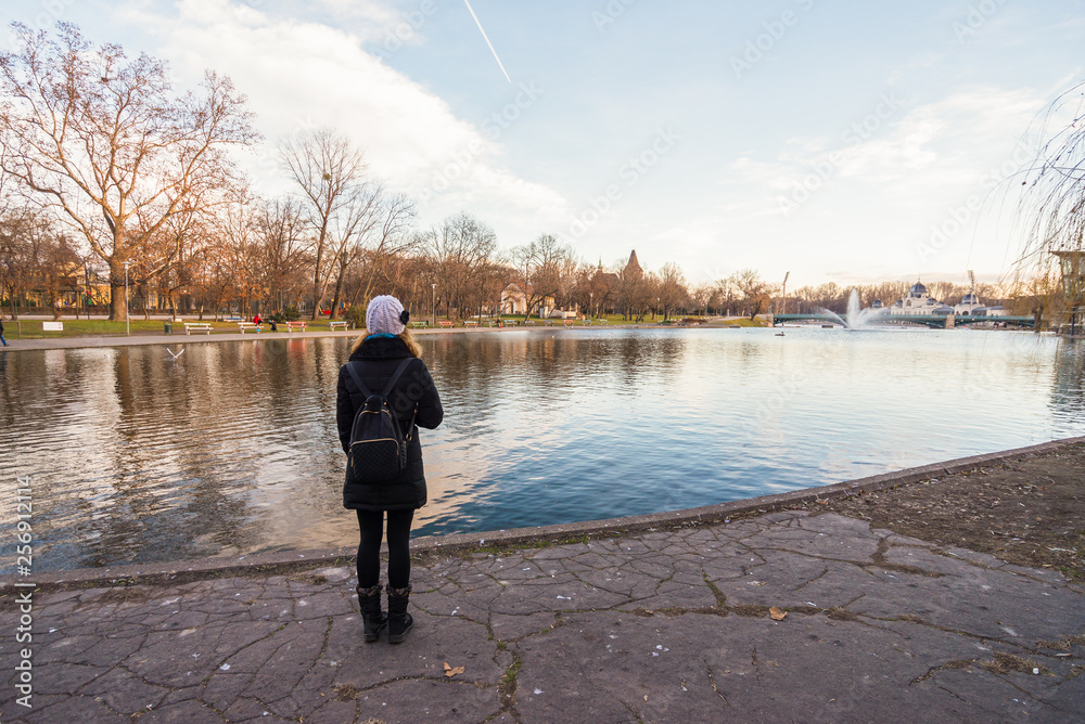 Young woman is standing by the lake in Budapest city park in Hungary.