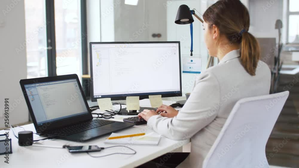 business, programming and technology concept - female programmer with script on computer screen working at office business, programming and technology concept - female programmer with script on computer screen working at office