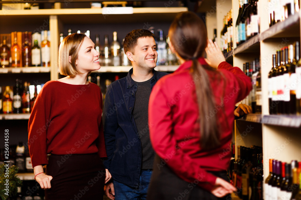 Image of woman, man and seller from back in store with wine