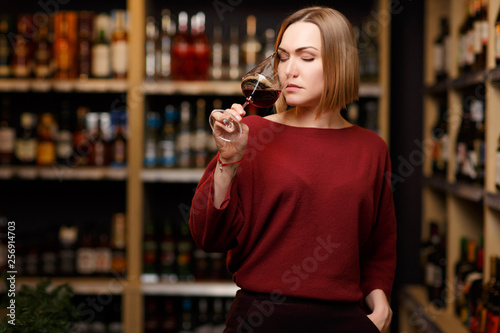 Image of blonde with glass in hands at store with wine