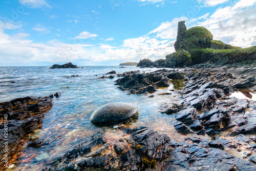 Fotografia Jagged rock layers and boulders smoothed by the ocean are seen at an intertidal zone on the island of Islay, Scotland, UK