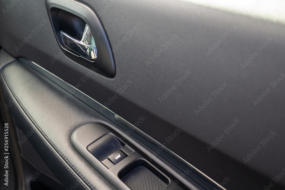 Car interior details of door handle with windows controls. Car window controls and details