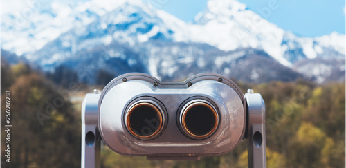 touristic telescope look at the city with view snow mountains, closeup binocular on background viewpoint observe vision, metal coin operated in panorama observation, travel nature concept photo