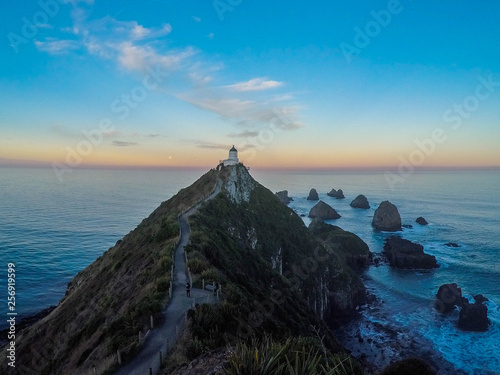 Scenic landscape panoramic view of Nugget Point Lighthouse while colorful sunset in summer. Tourist popular attraction/destination located in Catlins, Southland, South Island, New Zealand