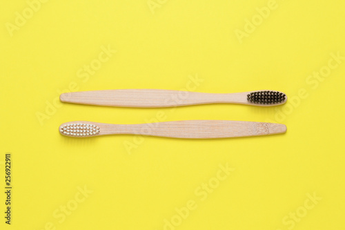 Bamboo toothbrushes on yellow background top view