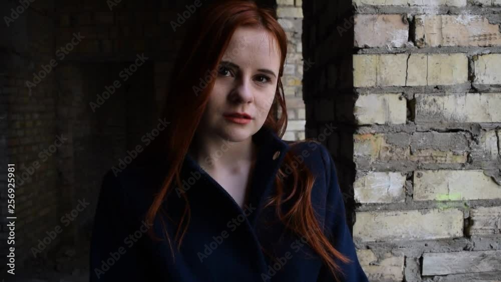 Portrait of a red-haired girl against a brick wall in the building. Portrait of a red-haired girl against a brick wall in the building.
