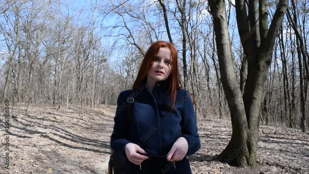 Red-haired young girl in blue coat. Dry forest. Red-haired young girl in blue coat. Dry forest.