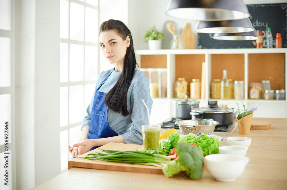 Portrait of young woman standing with arms crossed against kitchen background