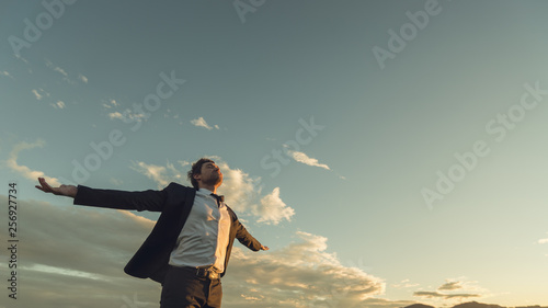 Young businessman relaxing under evening sky