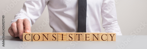 Wide view image of a businessman assembling word Consistency photo