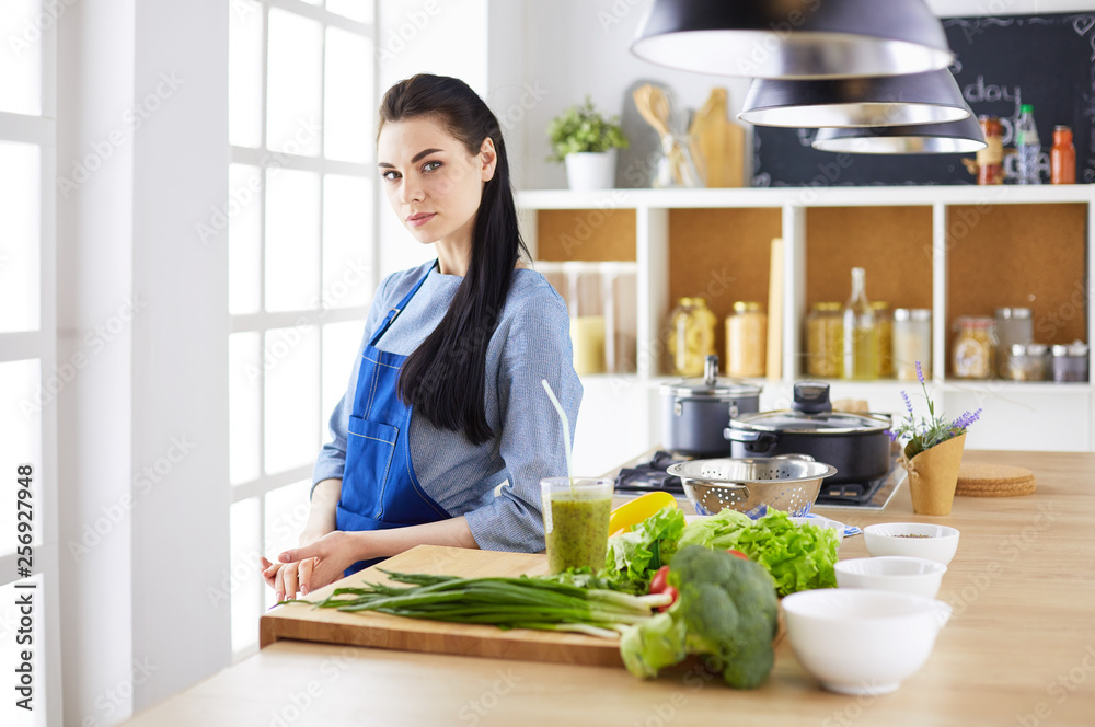 Portrait of young woman standing with arms crossed against kitchen background Portrait of young woman standing with arms crossed against kitchen background
