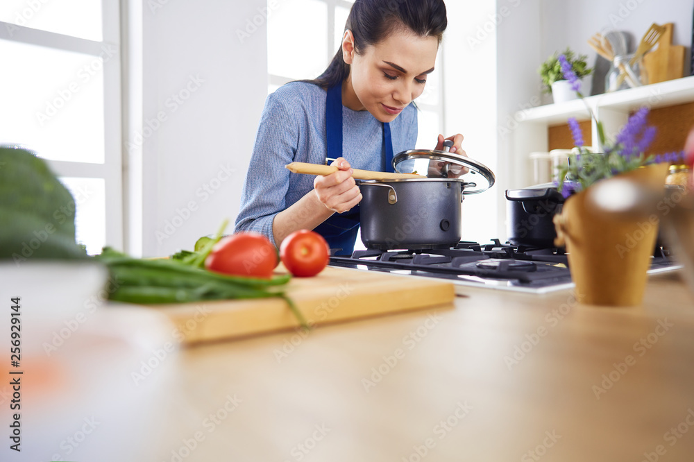 Cooking woman in kitchen with wooden spoon Cooking woman in kitchen with wooden spoon
