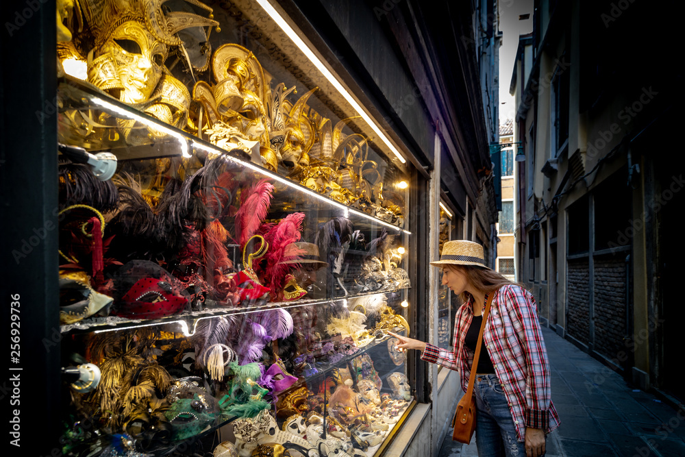 Young woman who chois a Venetian mask in shop