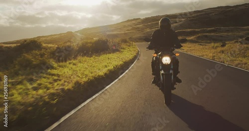 Motorcyclist riding fast at sunset on country road, motorcycle adventure lifestyle photo
