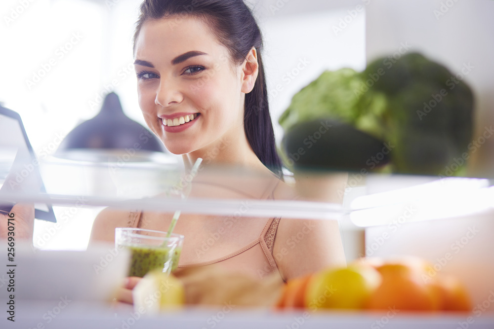 Smiling woman taking a fresh vegetable out of the fridge, healthy food concept Smiling woman taking a fresh vegetable out of the fridge, healthy food concept