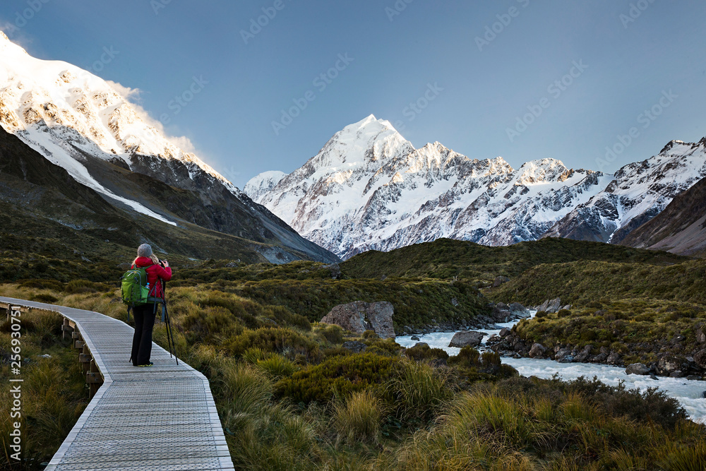 Naklejka premium Hiker photographer taking pictures of mt cook and the tasman river aoraki national park boardwalk
