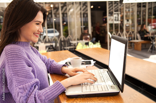 Young woman is working with computer in cafe