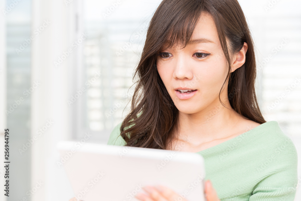 部屋でタブレットコンピューターを見る女性 驚く 部屋でタブレットコンピューターを見る女性 驚く